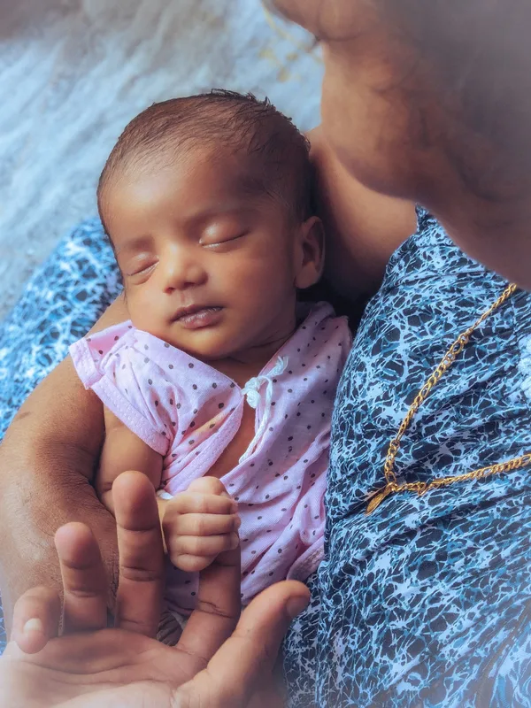 A newborn resting in their mother’s supporting arms.
