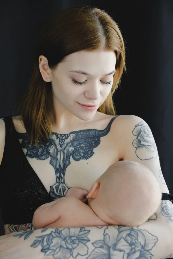 Mother breastfeeding her baby while looking down at the child.