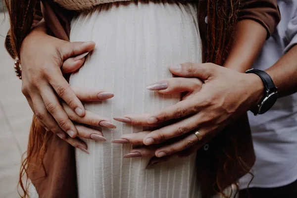 Expectant parents resting their hands on a pregnant belly.