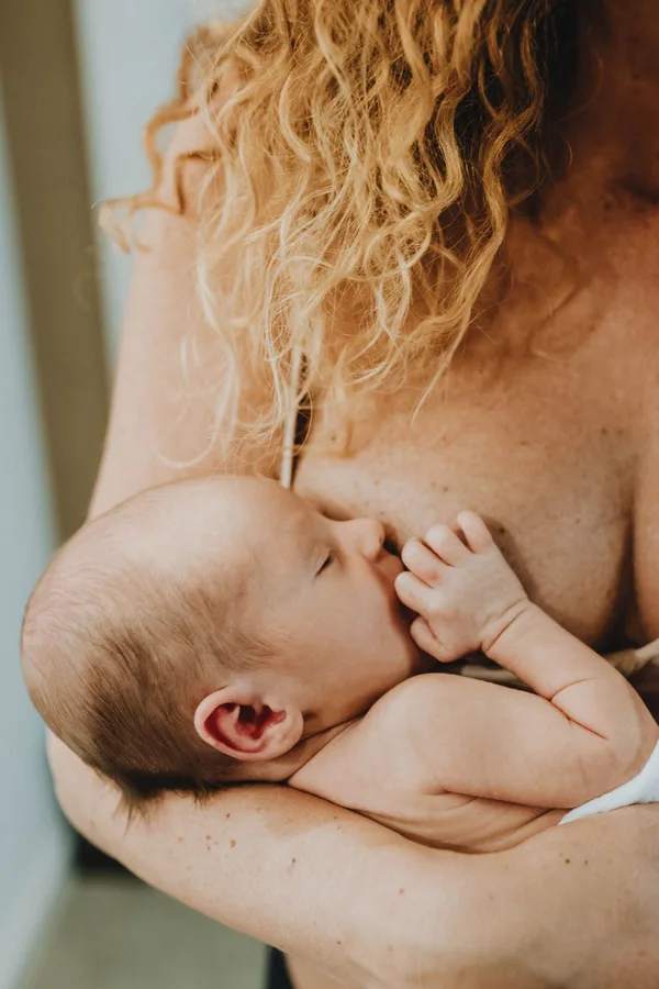 A mother breastfeeding her baby in her arms.