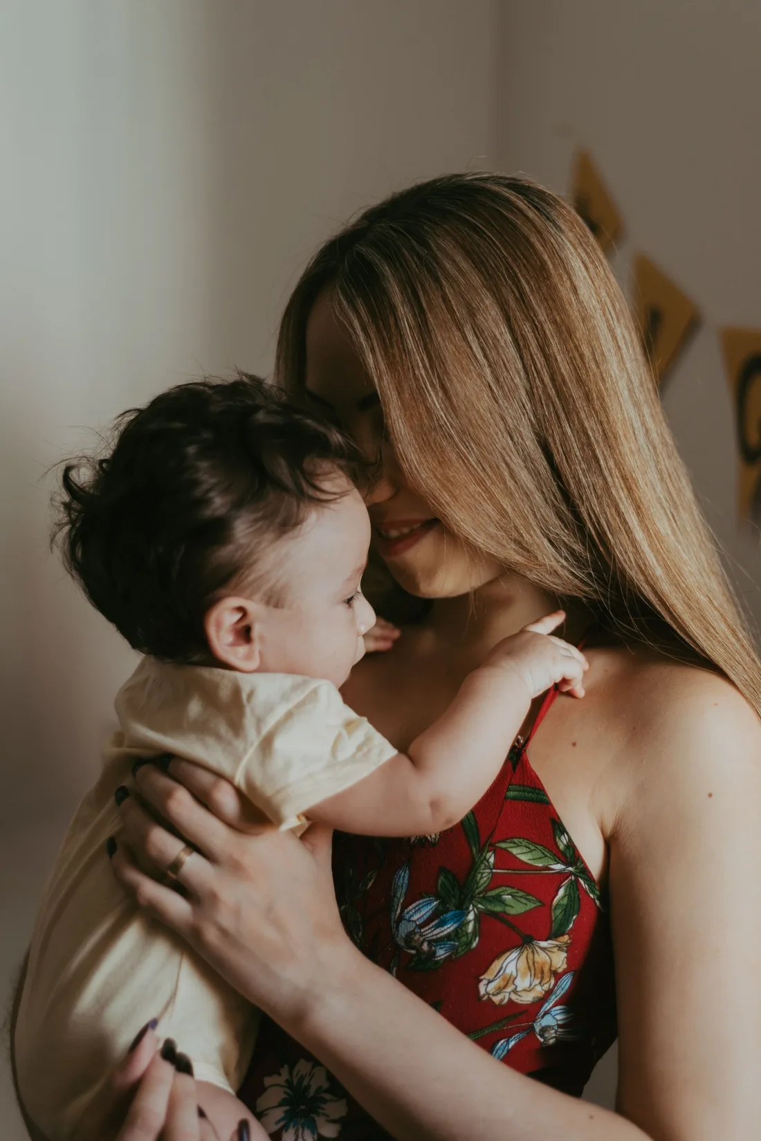 Mother holding her awake baby close, smiling down at the child.
