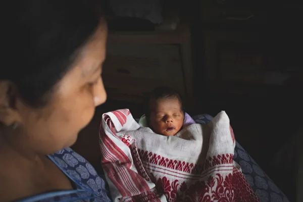 A parent watching their newborn resting in their arms.