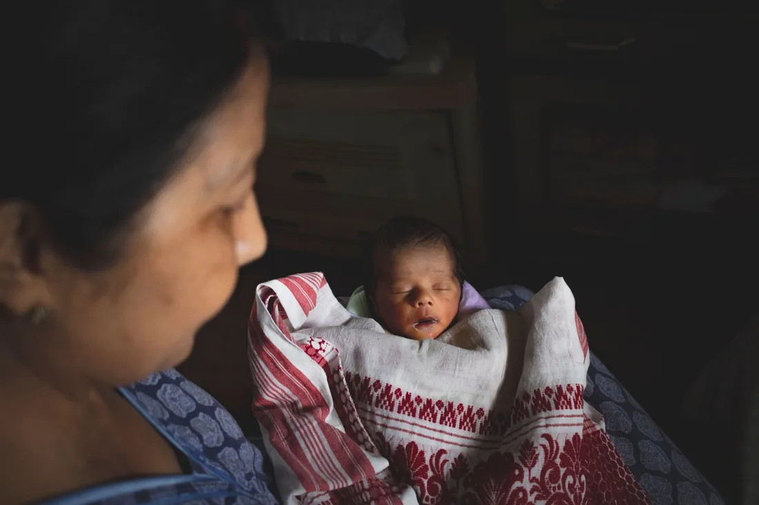 A parent watching their newborn resting in their arms.