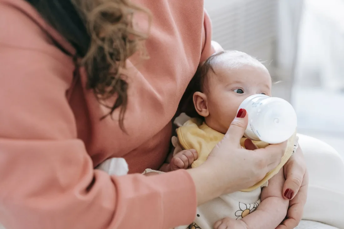 A mother supporting her baby during a bottle feed.