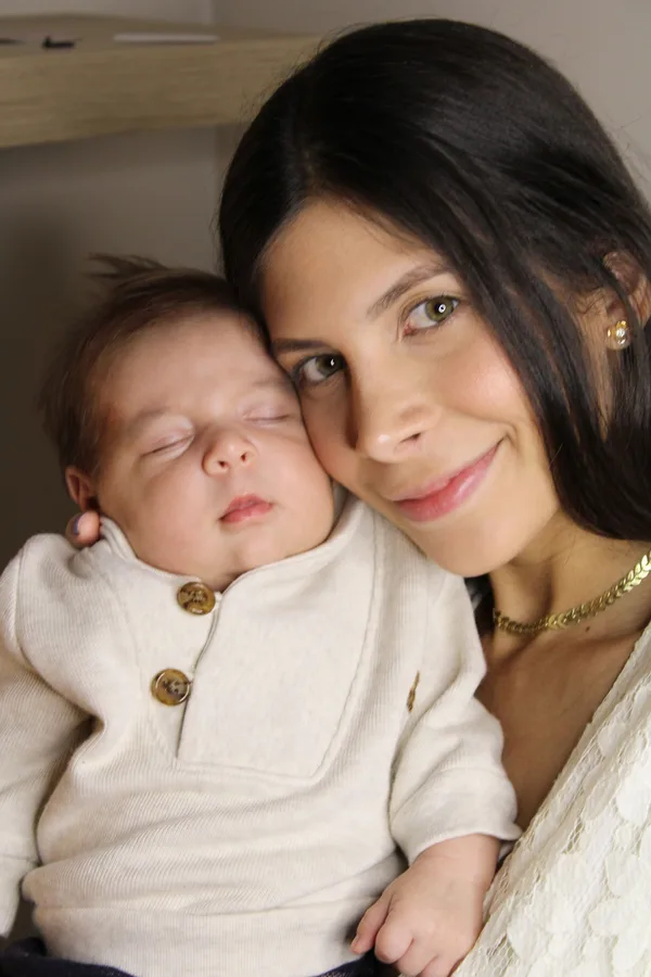 A mother holding her sleeping newborn close to her shoulder.